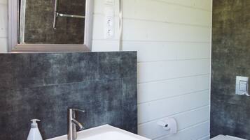 A bathroom with a white sink, a mirror, a toilet, and a shower.