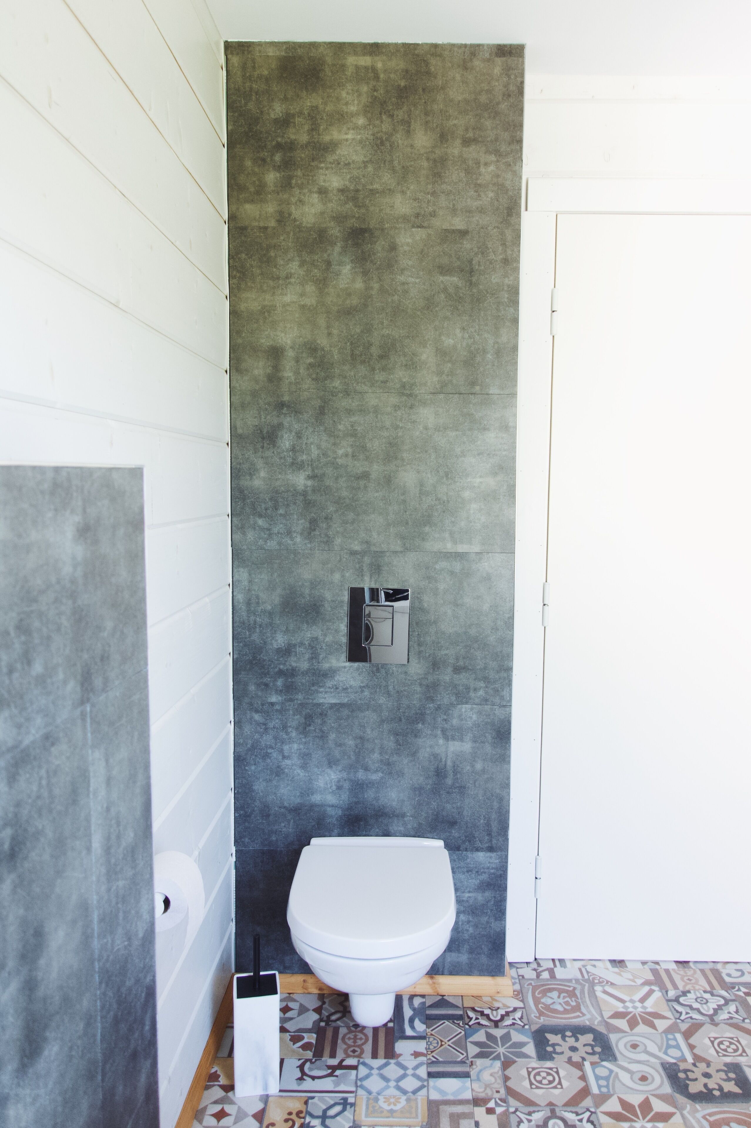 A bathroom with a white toilet, a towel dispenser, and a toilet paper holder on the wall.