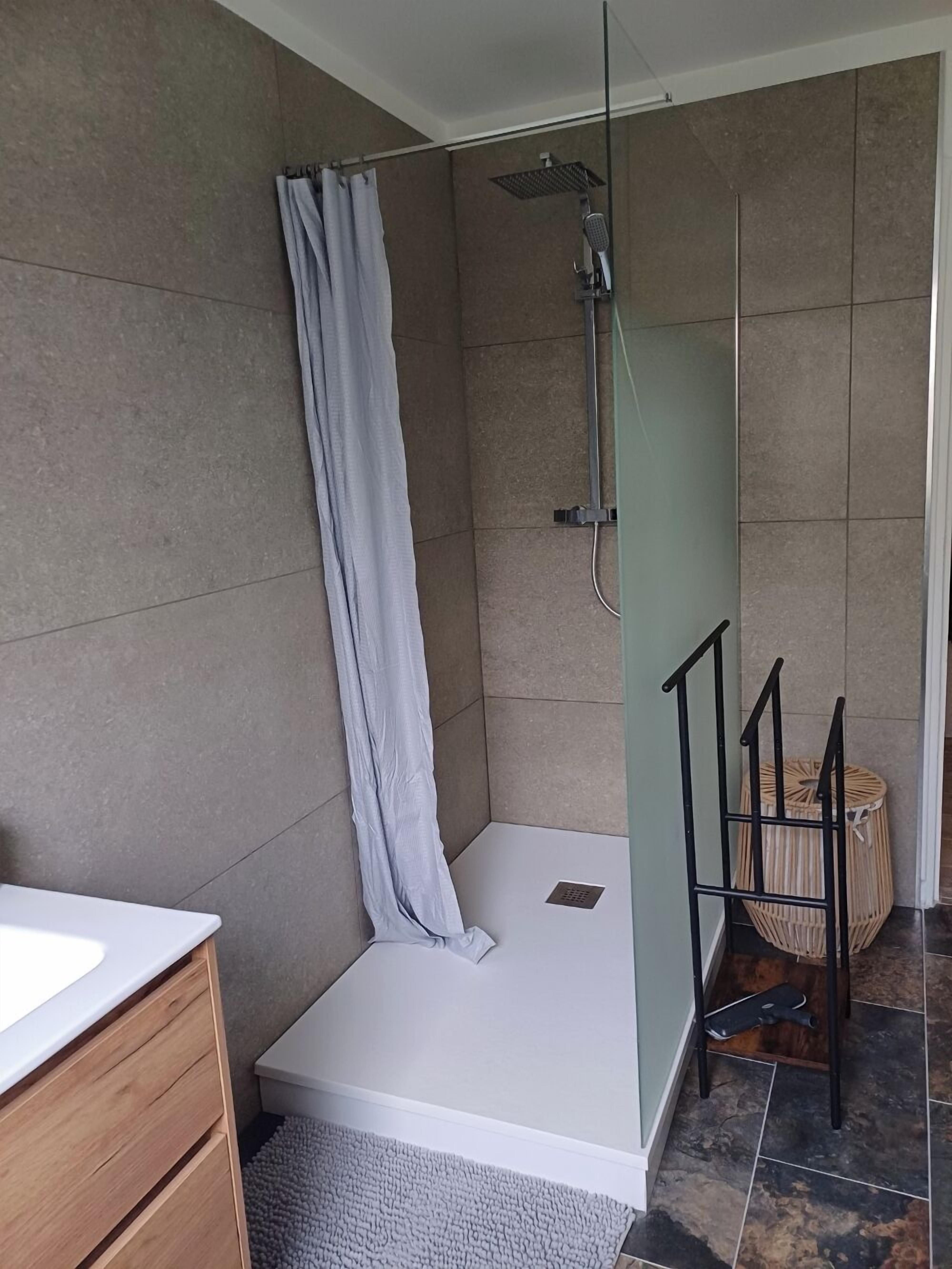 Une salle de bain moderne avec une douche, un lavabo blanc et un meuble en bois.