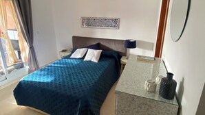 A bedroom with a bed, a nightstand, a dresser, a mirror, and a wall art piece. - Cozy apartment with private garden in Marbella (Marbella)
