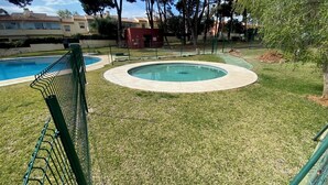 A swimming pool with a surrounding grassy area and a fence. - Cozy apartment with private garden in Marbella (Marbella)