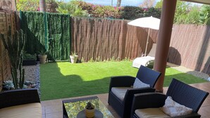 A patio area with wicker furniture, a glass-top table, and a small potted plant. - Cozy apartment with private garden in Marbella (Marbella)