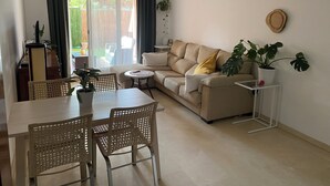 A living room with a sofa, dining table, chairs, a hanging light fixture, and a potted plant. - Cozy apartment with private garden in Marbella (Marbella)