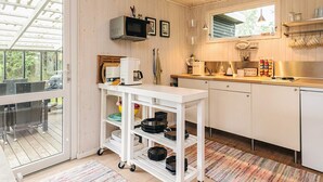 Una cocina compacta equipada con microondas, cafetera y un refrigerador pequeño. Hay una ventana que proporciona luz natural y vistas al exterior.