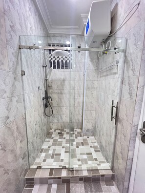 Modern shower with a handheld showerhead and wall-mounted faucet, set against a backdrop of marble tiles.