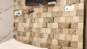 Una stanza con un letto, una televisione montata su una parete decorata e una presa di corrente.