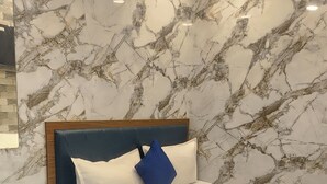 Camera da letto con un letto, un comodino in legno, pareti con motivo marmorizzato e luci a soffitto.