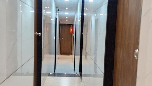 Un corridoio con pavimento in marmo, porte in legno e illuminazione a incasso.