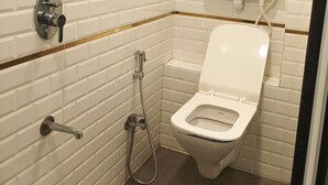 Un bagno con pareti piastrellate di bianco, un water, un bidet e una doccia.