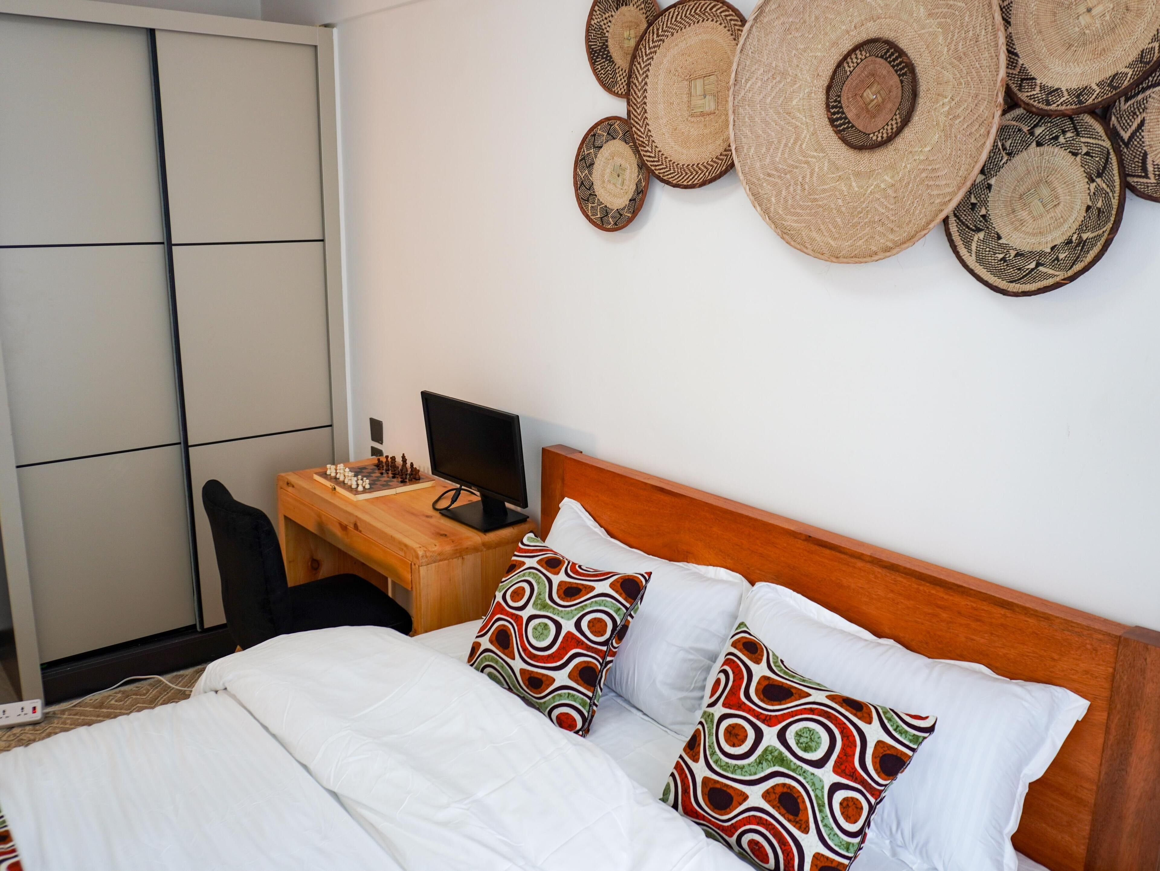 Een hotelkamer met een bed, een bureau met een computer en een kledingkast.