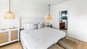 Quarto com cama grande, duas mesas de cabeceira, guarda-roupa e espelho.