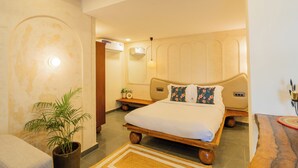 A bedroom with a wooden bed, a bedside table, a potted plant, and a wall-mounted air conditioner. - Hotel Green Park (New Delhi)
