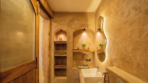 A bathroom with a wooden door, a white sink, a mirror, and shelves with plants. - Hotel Green Park (New Delhi)