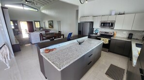 Enjoy cooking in this well-equipped kitchen with a large island, sink, and stainless steel appliances.