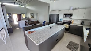 Enjoy cooking in this well-equipped kitchen with a large island, sink, and stainless steel appliances.