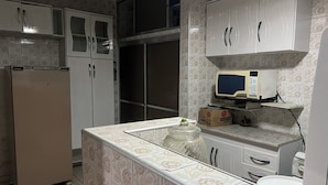 A kitchen with patterned tiles, a refrigerator, a microwave, and cabinets. - Corporate Accommodation (Parque das Universidades Campinas)