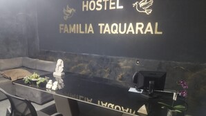 A reception desk with a black surface and gold lettering for "HOSTEL FAMILIA TAQUARAL". - Corporate Accommodation (Parque das Universidades Campinas)