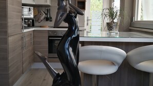 A modern kitchen with wooden cabinets, a marble countertop, and a unique black sculpture. - A peaceful stay through culture and relaxation. Directly on the lake (Villaggio Sanghen)