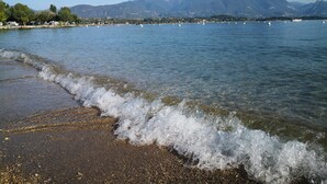 A beach with clear water, waves, and mountains in the background. - A peaceful stay through culture and relaxation. Directly on the lake (Villaggio Sanghen)