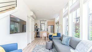 Een moderne woonkamer met een grijze bank, blauwe fauteuils en een kamerbreed tapijt met patroon.