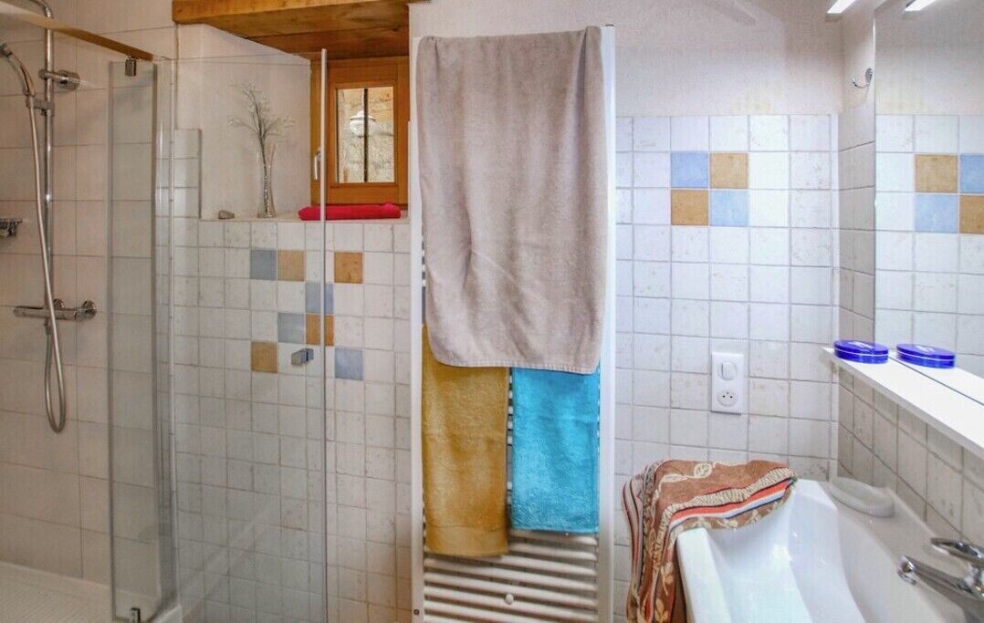 A bathroom with a shower, a bathtub, and a toilet. There are towels hanging on a rack.