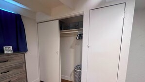 Een kamer met een houten dressoir, een gesloten kast en een prullenbak.