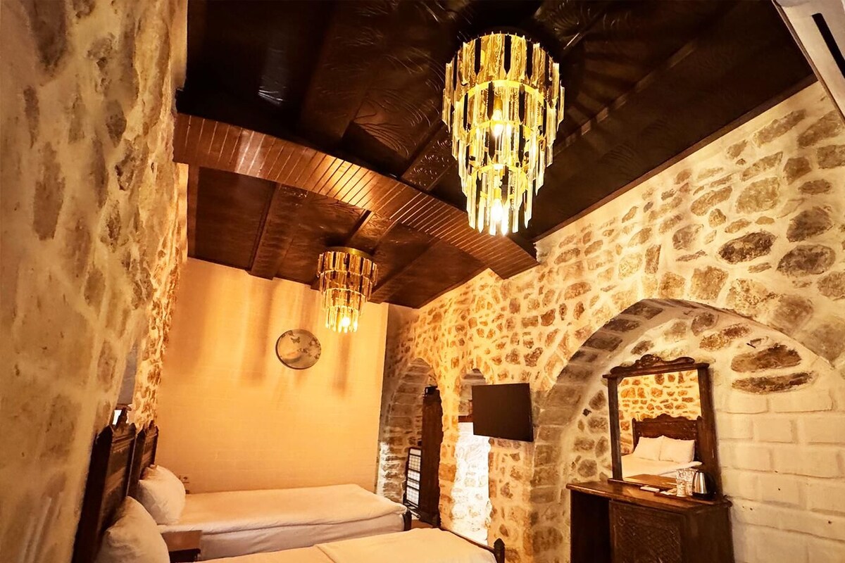 A cozy room with a stone wall, a wooden ceiling, and a chandelier.