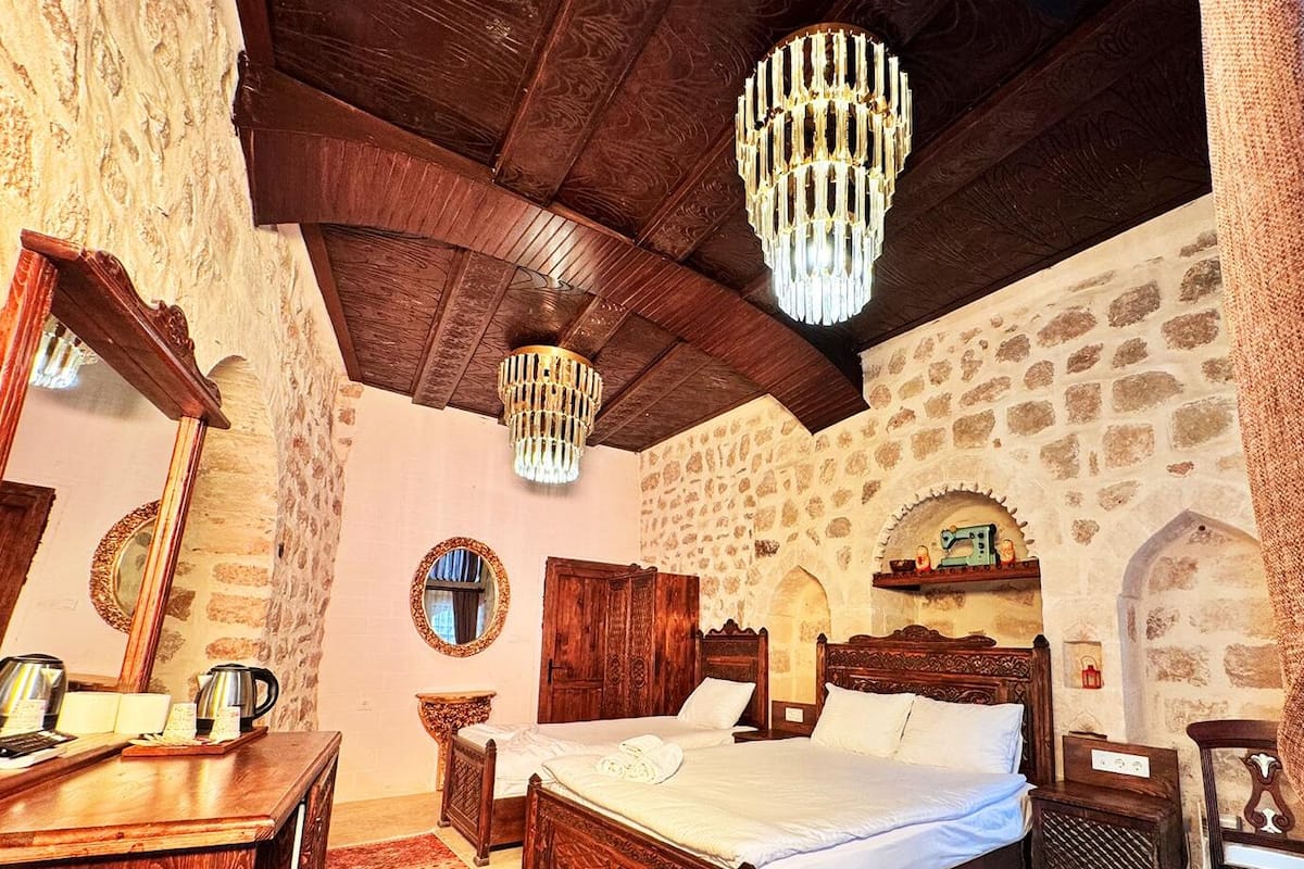 A traditional room with a bed, wooden furniture, stone walls, and a chandelier.