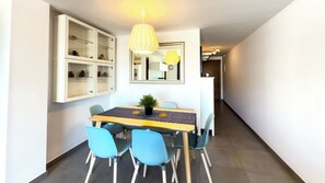 Uma área de refeições com uma mesa, cadeiras, um vaso de planta e um espelho na parede.