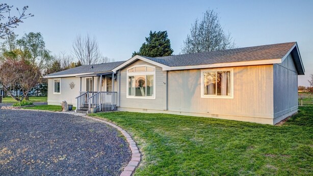 A single-story house with a front porch, a small deck, and a gravel driveway. - 3BR Retreat in Prosser Perfect for Wine Lovers (Prosser)
