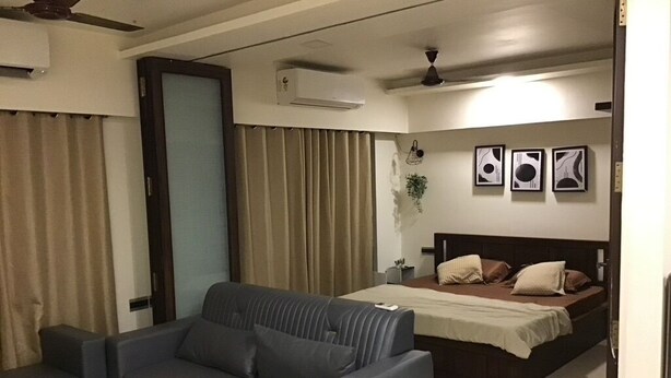 Una camera d'albergo moderna con divano, un letto, un tavolino e una ventola a soffitto.