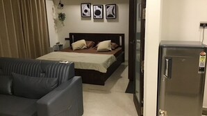 Una camera d'albergo con un letto, un divano, un frigorifero e un accesso al bagno.