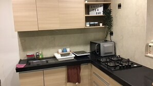 Una cucina con mobili in legno, un piano di lavoro nero, un forno a microonde, un piano cottura a gas e un cartello che indica una zona caffè.