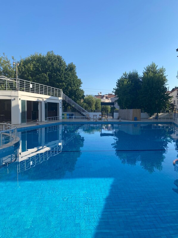 Una piscina al aire libre de temporada, sombrillas