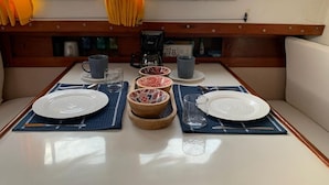 Een eethoek met een tafel gedekt voor twee personen, inclusief een koffiezetapparaat, kopjes en kommen.