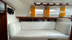 Een chalet met een witte, beklede bank, houten sierlijsten en gele gordijnen.