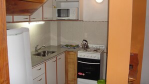 A compact kitchen with a built-in microwave, a gas stove, and a refrigerator.
