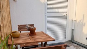 Een houten tafel en stoelen tegen een witte muur, met een gesloten luik.