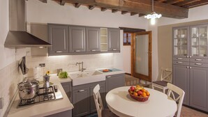 Una cocina moderna con gabinetes grises, encimera blanca y cocina a gas.