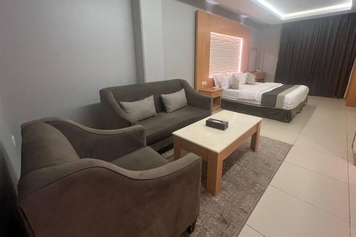 A modern hotel room with a sofa set, a bed, and a small table.