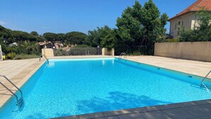 Ein rechteckiger Swimmingpool mit klarem, blauen Wasser, umgeben von einer gefliesten Liegefläche und Metallgeländern.
