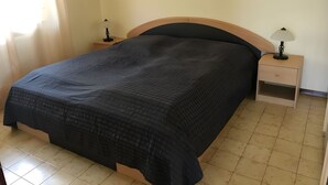 A bedroom with a bed, two bedside tables, a nightstand, a lamp, and a framed picture on the wall. - Vacation apartment Lake Garda Cavaion Bardolino with pool (Cavaion)