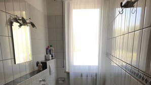 A bathroom with a toilet, sink, and mirror. There is a window with curtains, and the floor is tiled. - Vacation apartment Lake Garda Cavaion Bardolino with pool (Cavaion)