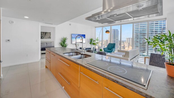 A modern kitchen with a large island, stainless steel appliances, and a view of the city skyline. - Sun, Style & Skyline | Modern Icon Brickell 2BR (Miami)