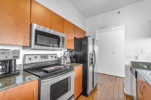 A modern kitchen with stainless steel appliances, wooden cabinets, and granite countertops.
