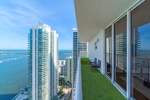 A balcony with a view of tall buildings and a body of water.
