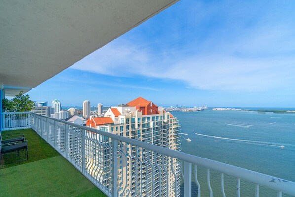 A high-rise building with a red roof and multiple balconies overlooking a body of water.