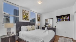 A modern hotel room with a large bed, a cityscape view, and artwork on the walls. - City-View Retreat in Brickell 2BR + Free Parking (Miami)