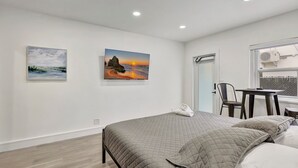 A modern bedroom with a bed, two paintings, a desk, and a chair. - Studio off Las Olas- Steps to the Beach (Fort Lauderdale)