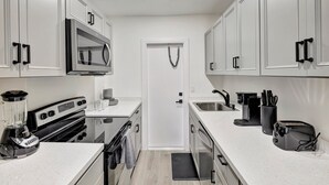 A modern kitchen with white cabinets, a built-in microwave, a stove, a coffee maker, and a toaster. - Studio off Las Olas- Steps to the Beach (Fort Lauderdale)